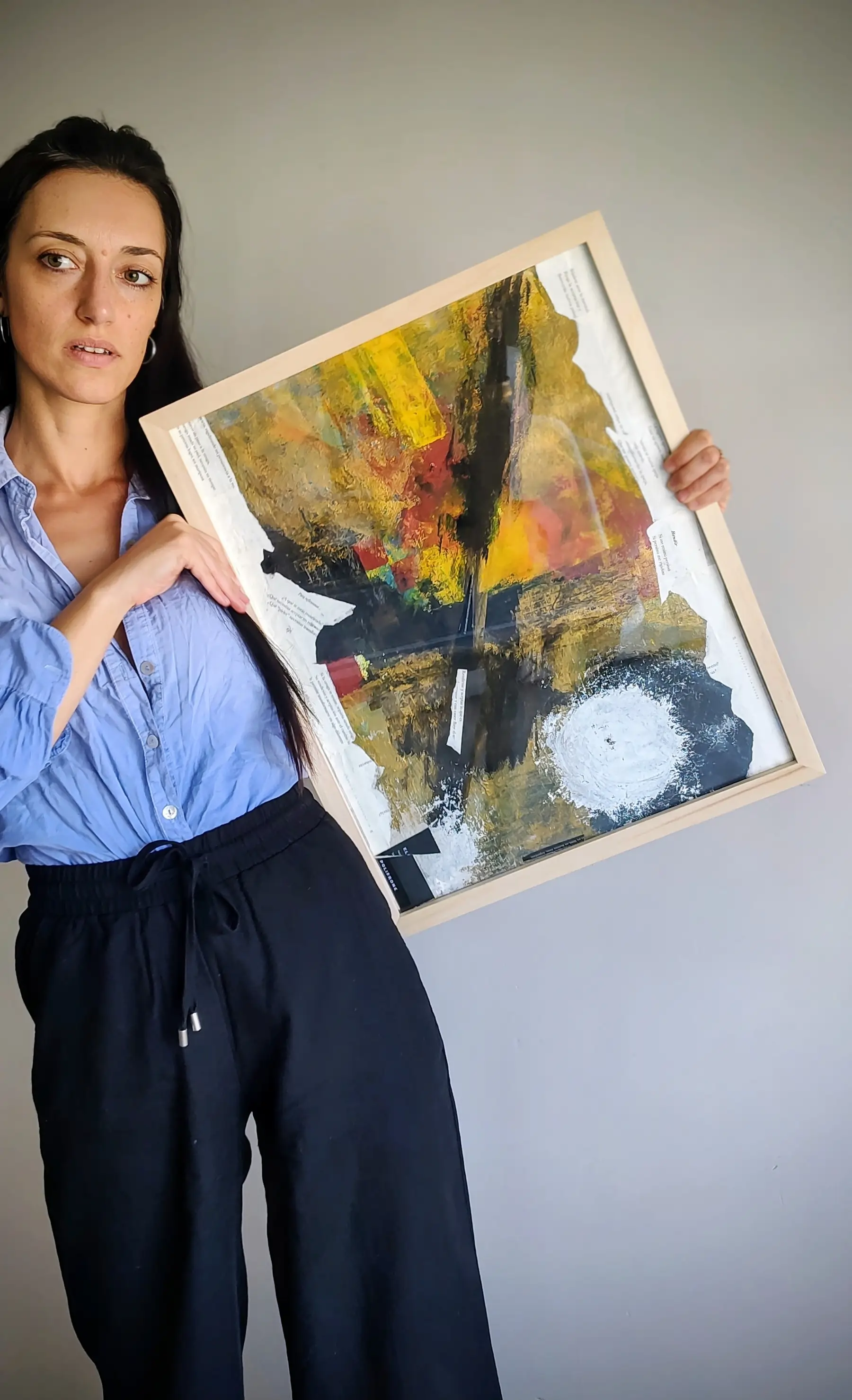 Eliana Polifrone sosteniendo una obra de arte, integrando disciplinas creativas y holísticas en su método de coaching.